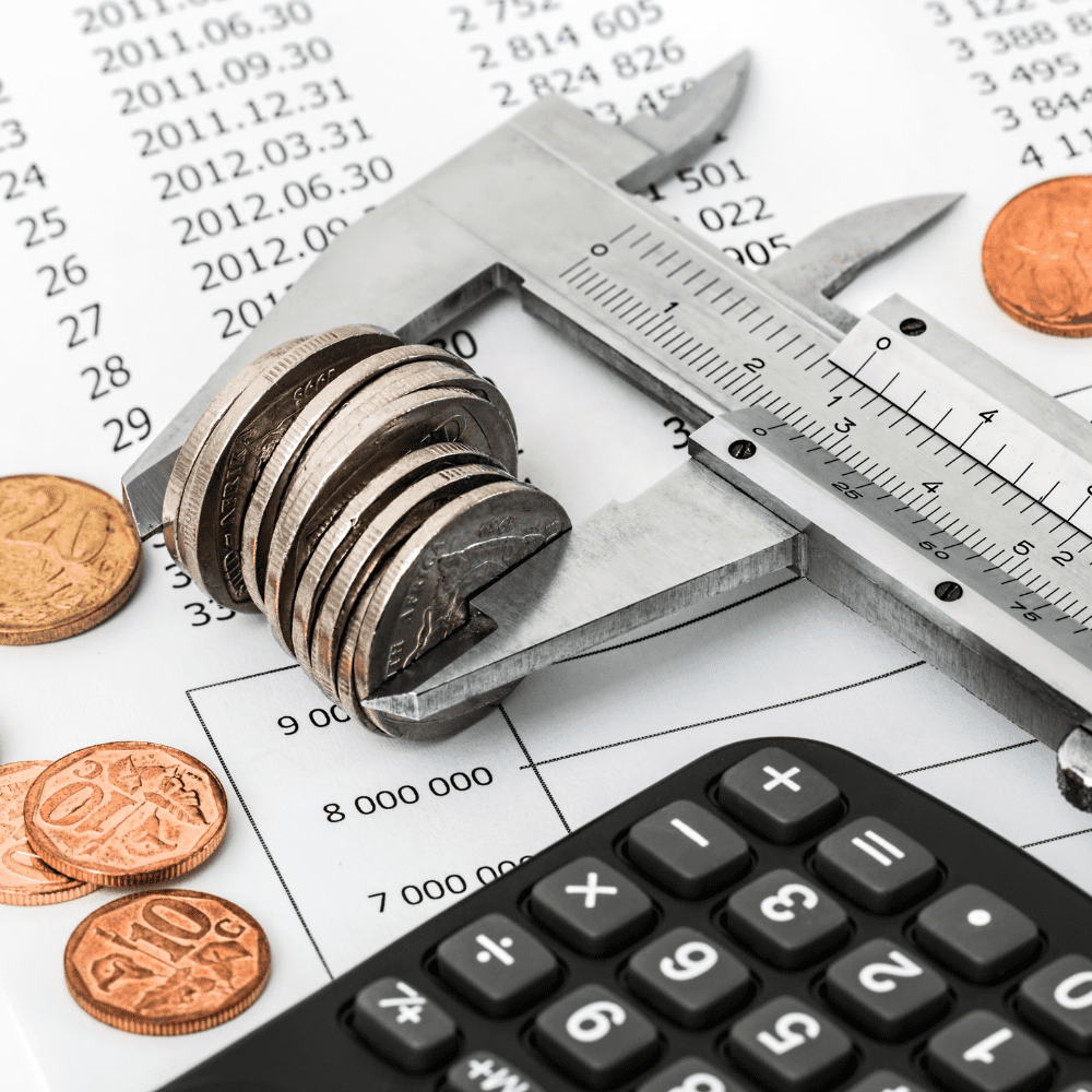 A calculator, coins and a ruler on top of a table.