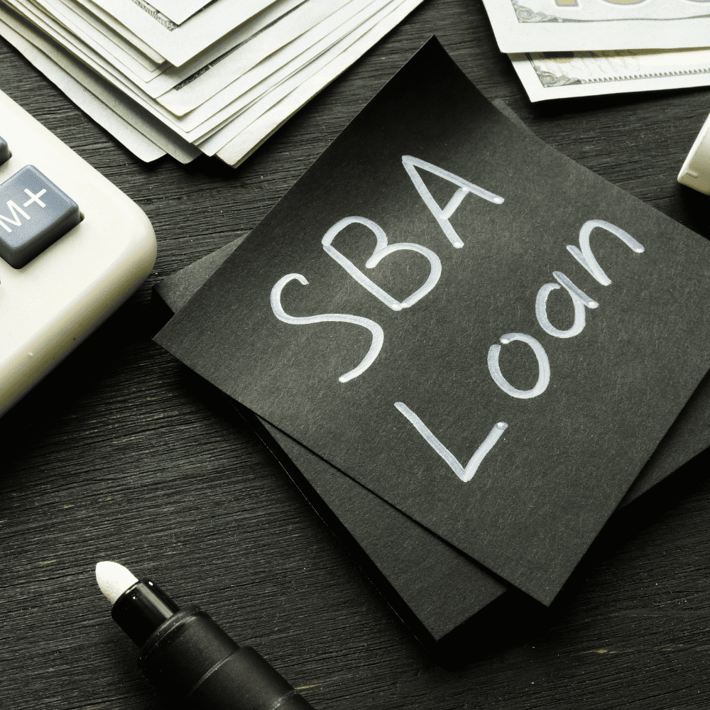 A note that says sba loan on top of a desk.