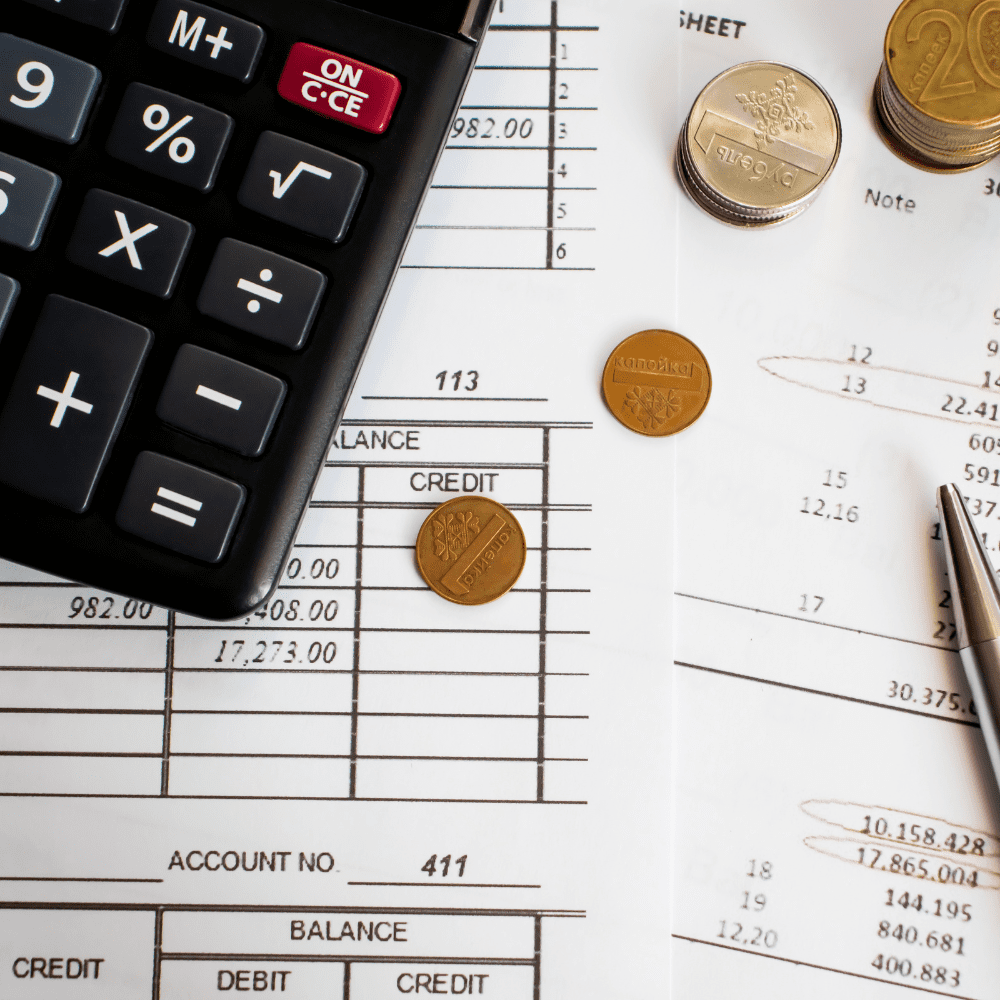 A calculator and some coins on top of paper.